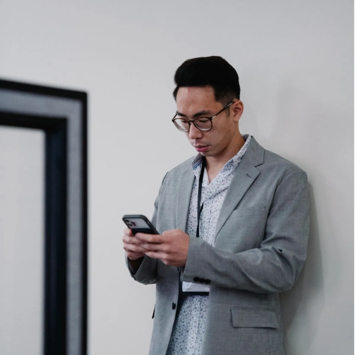 Agent de sécurité en costume consultant des offres via smartphone. Agent de sécurité en costume.