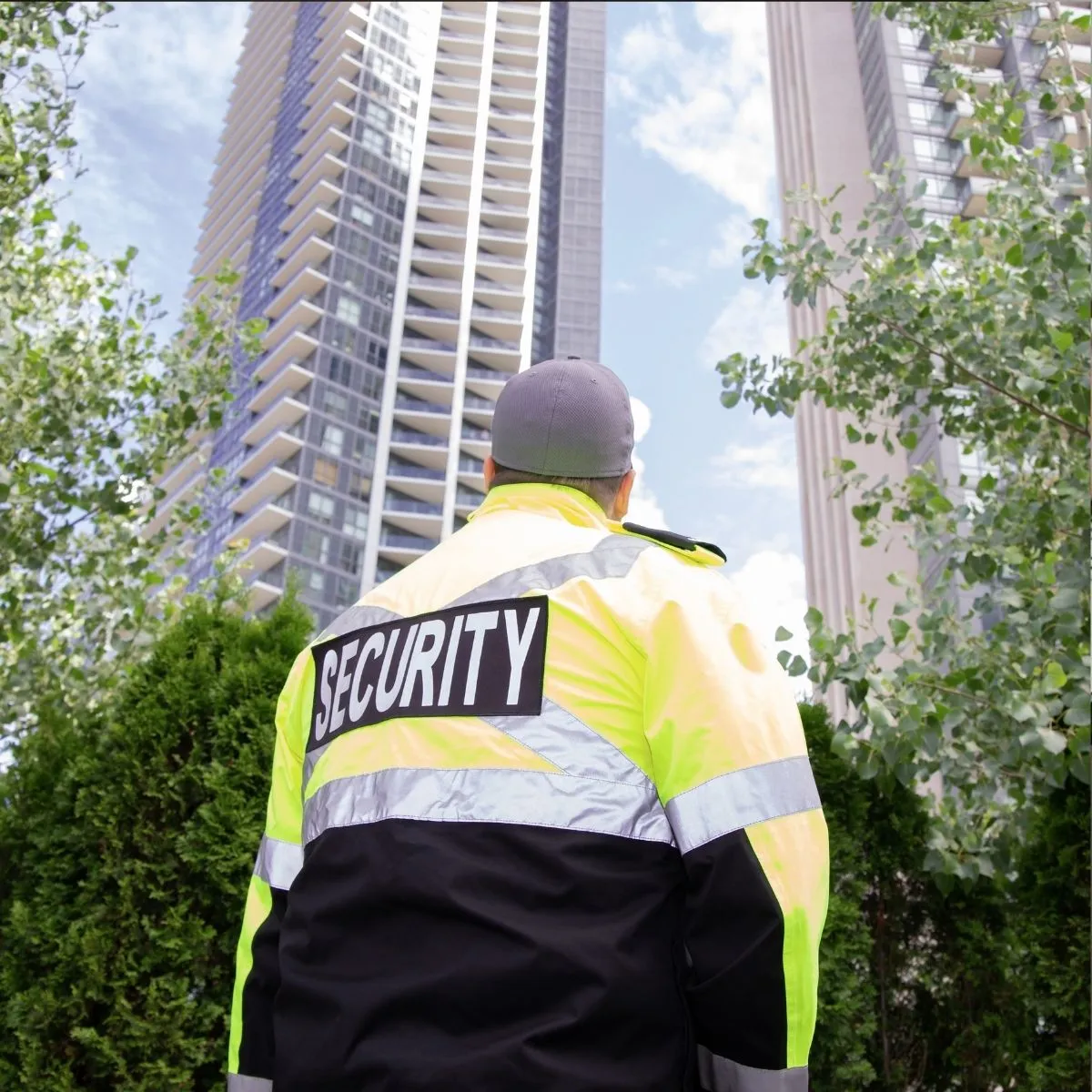 Un agent de sécurité privé en uniforme avec gilet réfléchissant patrouillant à l’extérieur d’un bâtiment. Un agent de sécurité privé en uniforme avec gilet réfléchissant.